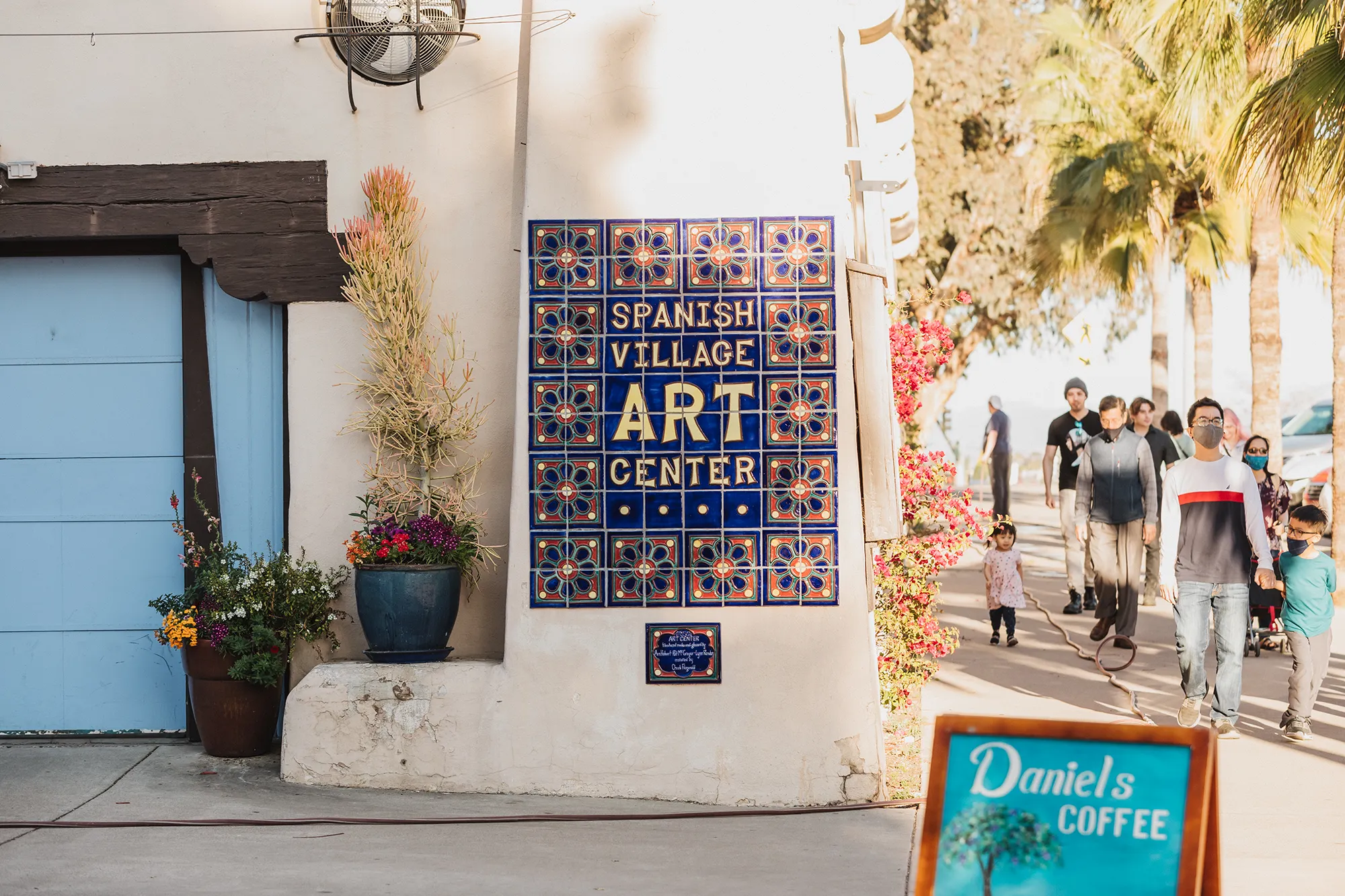 A multi-color tiled sign on a building that says Spanish Village Art Center.