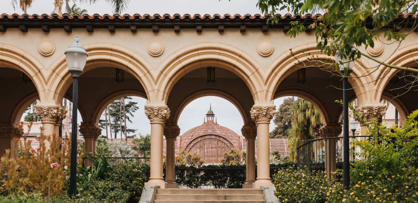 A view of the Balboa Park Botanical Building roof looking through the arch of a covered walkway.