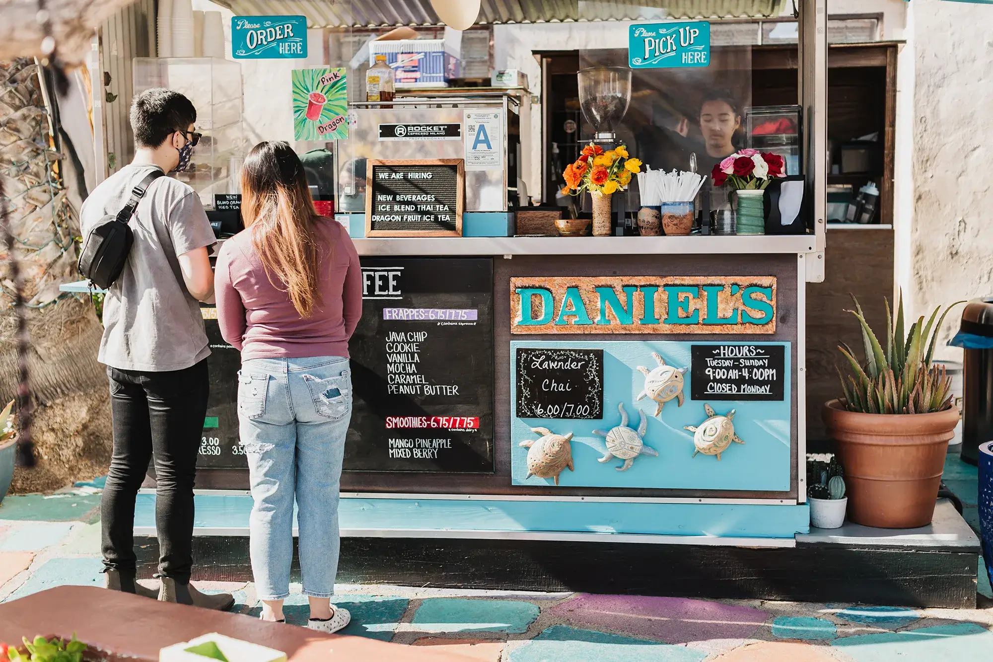 Two people standing outside Daniels coffee stand