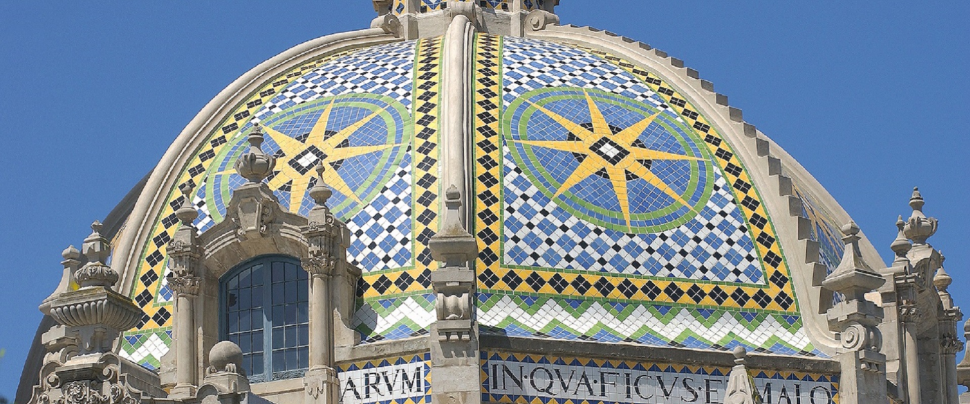 Tiled geometric designs with yellow, blue, green, and white on a dome in Balboa Park.