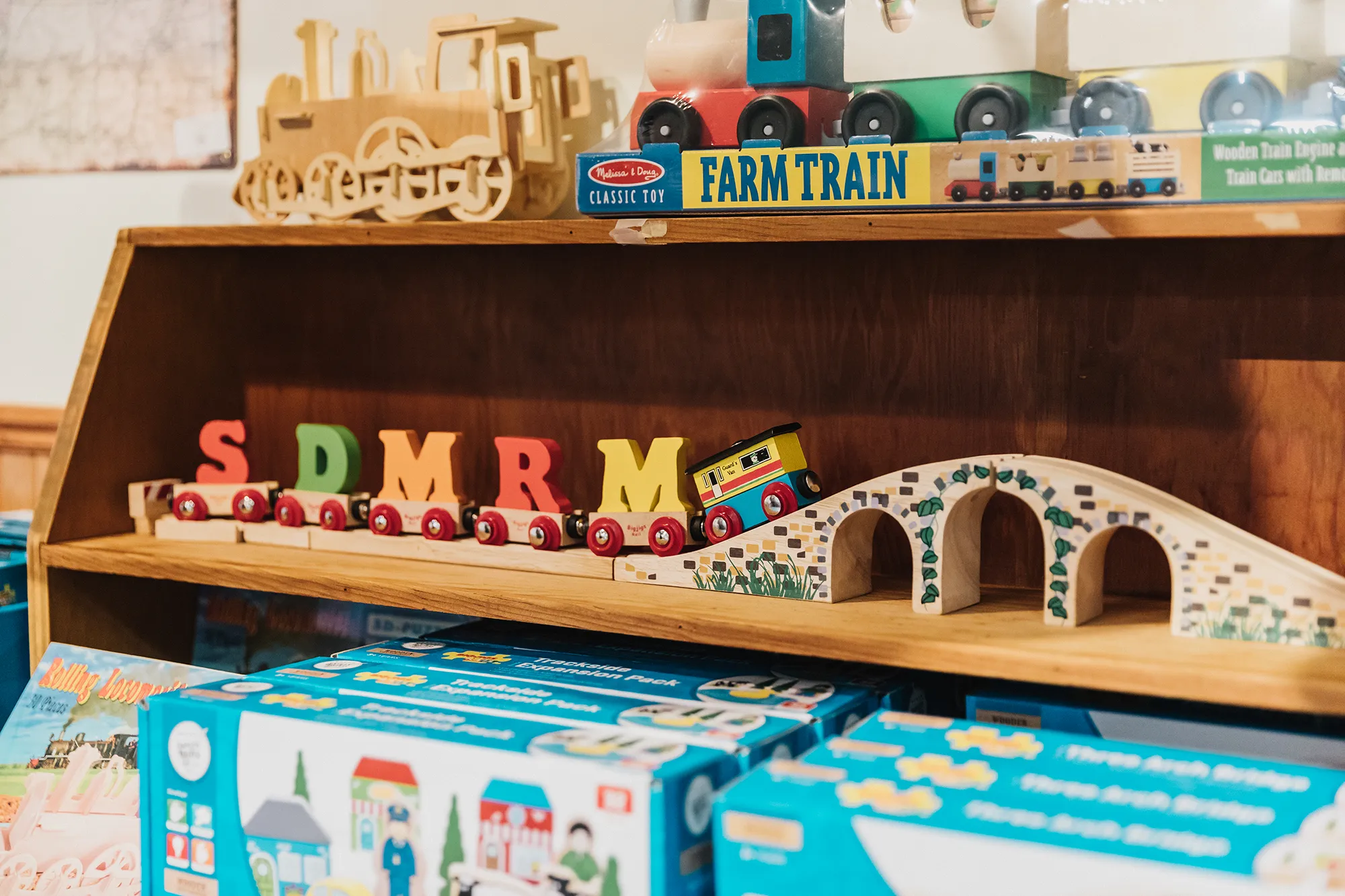 A display of wooden trains on tracks carrying colored letters SDMRM in the San Diego Model Railroad Museum gift shop.