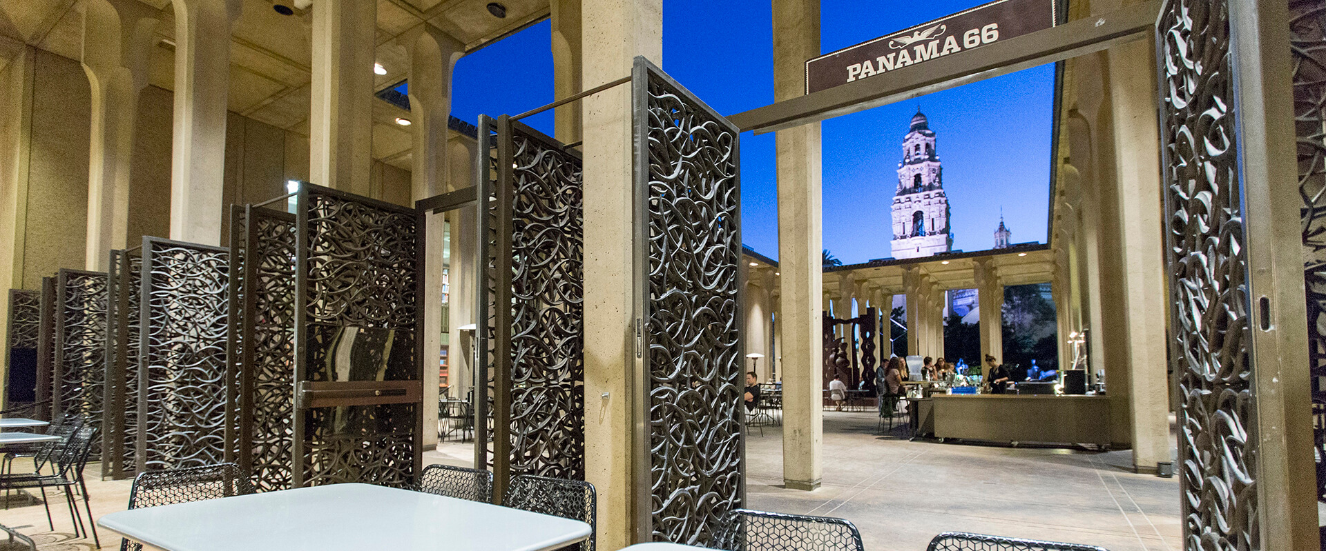 Detailed metal door entrance to Panama 66 at the San Diego Museum of Art. The bar and California Tower can be seen in the background.