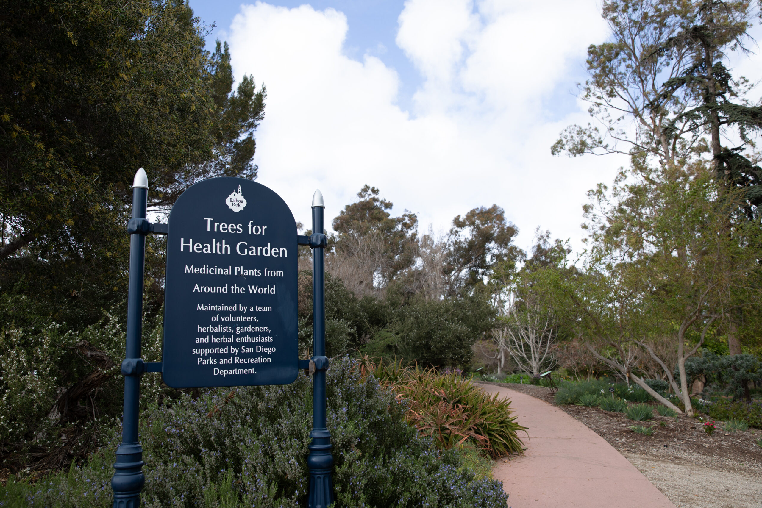 Trees for Health Garden sign that states the garden has medicinal plants from around the world and is maintained by a team of volunteers, herbalists, gardeners, and herbal enthusiasts support by San Diego Parks and Recreation Department.
