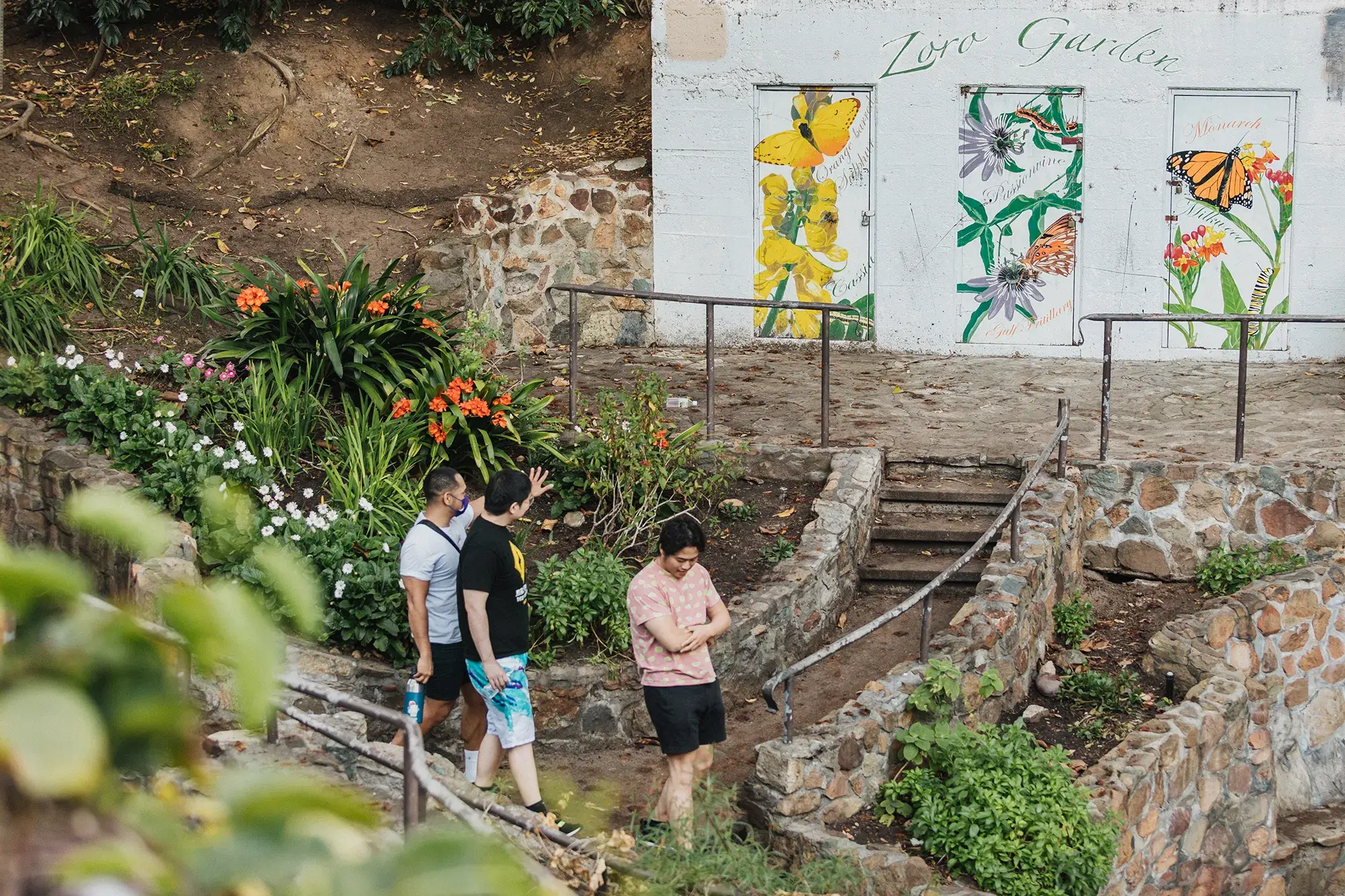 Three people walking down a stone walled ramp into Zoro Garden.