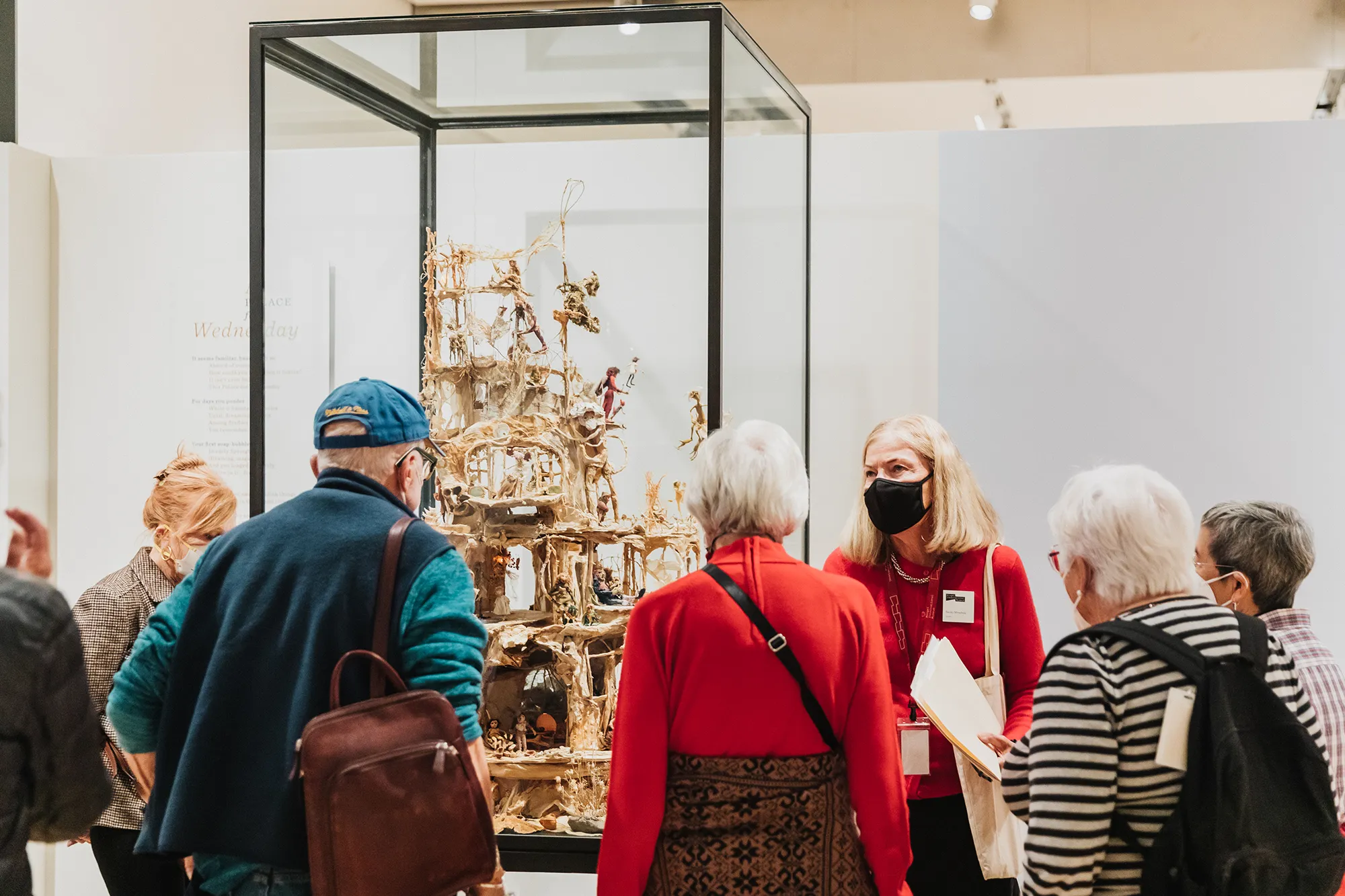 A group of people looking at a an object on display inside of the Mingei International Museum.