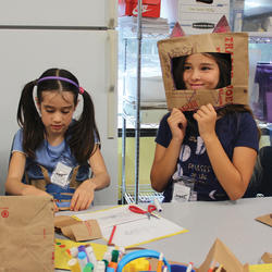 Two children working on an activity with paper bags and markers.