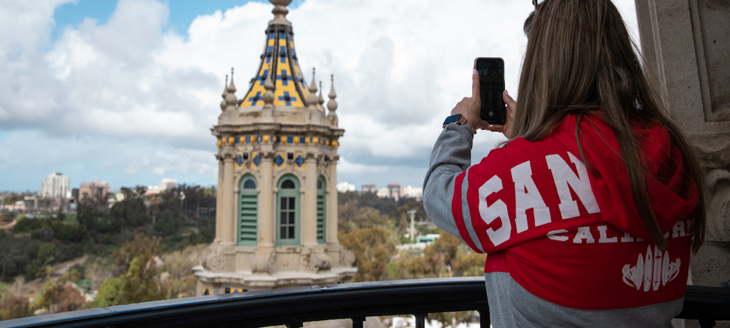Woman with red and grey hoodie taking a photo of the California tower