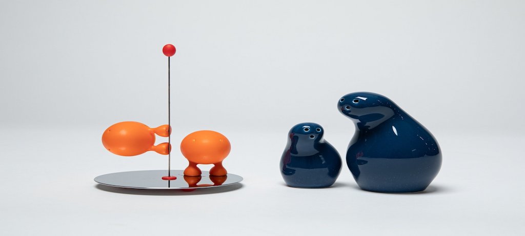 two orange spheres on a silver pole with a red dot on top, Two blue bowling pin type objects are next to them.