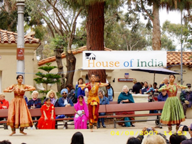 people preforming on a stage outside in front of sign that says house of India