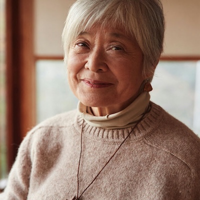 older woman with short white hair in a grey sweater