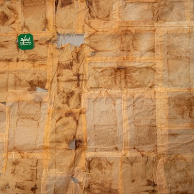 brown tattered fabric with a green tag on the upper left corner