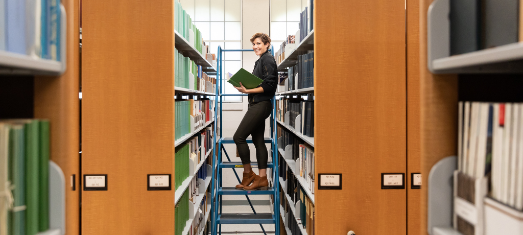 Person standing in between bookshelfs