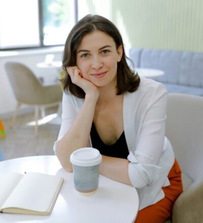 woman sitting at a table with a coffee and book in front of her