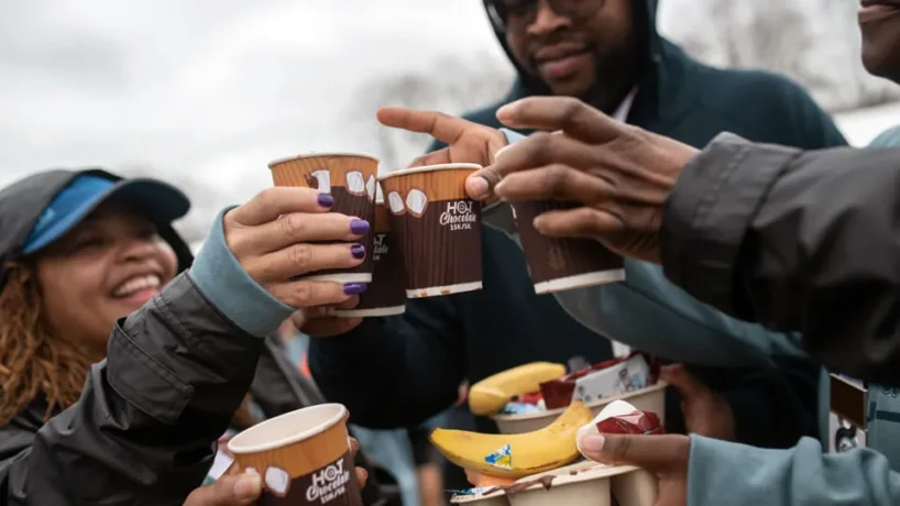 Group of people toasting cups of hot chocolate and holding bananas