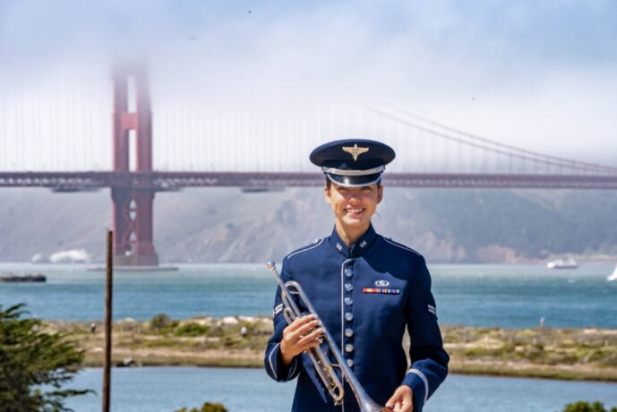 female veteran standing in front of the golden gate bridge with a horn instrument