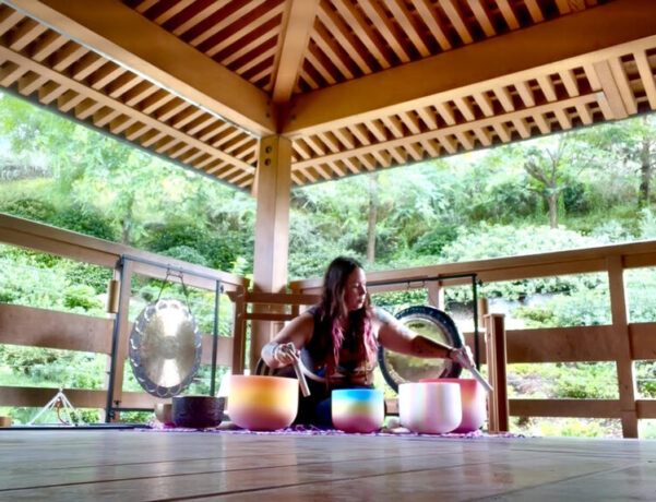 woman sitting in pavilion with sound bowls surrounding her