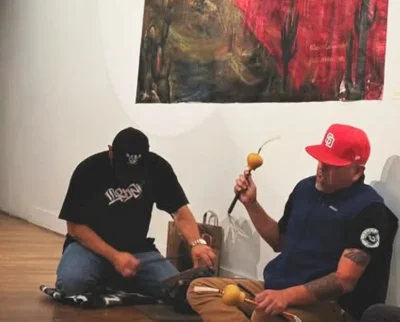 two people sitting on the ground playing the drums