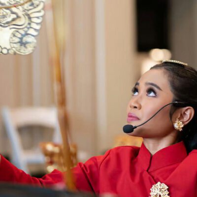 Woman wearing a red shirt and a headset microphone looking up