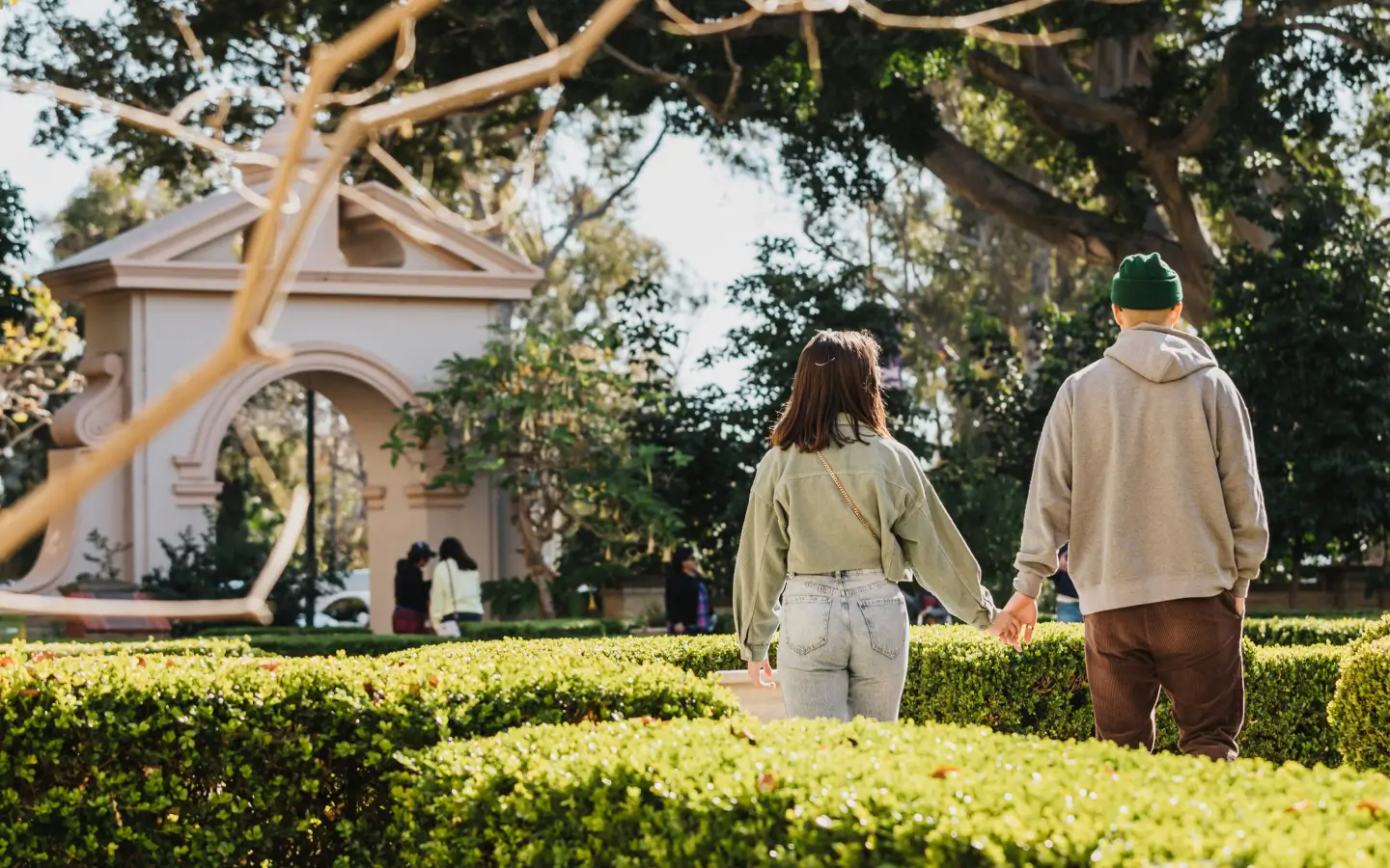 Two adults holding hands and walking in the Alcazar garden